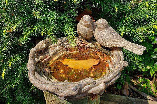 Wonderful small garden bird bath, with two model birds on the side of the bath and a leaf in the water.